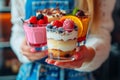 A girl carrying a tray with different desserts in a glass.A tray of sweet desserts. Sweet dessert in a glasses with berries, mint