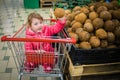 A girl in a cart buys coconuts in a supermarket. The child purchases cokes Royalty Free Stock Photo