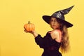 Girl with carved orange pumpkin isolated on warm yellow background Royalty Free Stock Photo