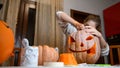 A girl carving big orange pumpkin into jack-o-lantern for Halloween holiday decoration at kitchen. Decoration for party Royalty Free Stock Photo