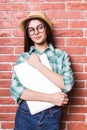 girl in casual clothes, hat and eyeglasses posing, smiling and with close laptop in hands