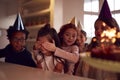 Girl Celebrating Birthday With Group Of Friends At Home Being Given Cake Decorated With Sparkler Royalty Free Stock Photo