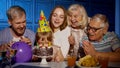 Girl celebrating birthday party with parents, senior grandparents family blowing out candles on cake Royalty Free Stock Photo