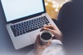 Girl in a chair in a homely atmosphere with an open laptop with a empty blank screen monitor and a cup of coffee or tea Royalty Free Stock Photo