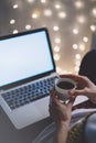 Girl in a chair in a homely atmosphere with an open laptop with a empty blank screen monitor and a cup of coffee or tea