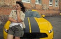 Girl Charlie Watson stands near yellow car with the autobot logo or robot transformer Bumblebee Royalty Free Stock Photo