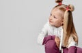 Girl with charming smile sitting on floor in fashionable training suit on a gray background Royalty Free Stock Photo