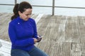 A girl chatting on the pier, connecting with the world through her mobile phone