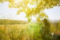 Girl in the checkered shirt is sitting in the autumn forest. Seasonal concept. Stylish hipster clothes outdoors. Nature philosophy