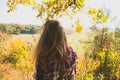 Girl in the checkered shirt is sitting in the autumn forest. Seasonal concept. Stylish hipster clothes outdoors. Nature philosophy Royalty Free Stock Photo