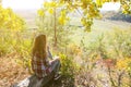 Girl in the checkered shirt is sitting in the autumn forest. Seasonal concept. Stylish hipster clothes outdoors. Nature philosophy Royalty Free Stock Photo