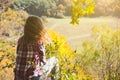 Girl in the checkered shirt is sitting in the autumn forest. Seasonal concept. Stylish hipster clothes outdoors. Nature philosophy Royalty Free Stock Photo