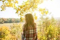 Girl in the checkered shirt is sitting in the autumn forest. Seasonal concept. Stylish hipster clothes outdoors. Nature philosophy Royalty Free Stock Photo