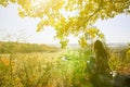 Girl in the checkered shirt is sitting in the autumn forest. Seasonal concept. Stylish hipster clothes outdoors. Nature philosophy Royalty Free Stock Photo