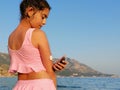 Girl checks glucose level with CGM device before enters the sea. On the right arm is placed white sensor witch send information