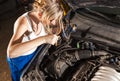 Girl checks the oil level in the car