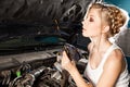 Girl checks the oil level in the car