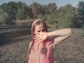 A girl with cheerful, playful, mischievous eyes covers her face with her hand. A cute young woman in pink clothes in the park, Royalty Free Stock Photo