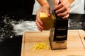 Girl chef rubs fresh fragrant cheese on a grater for making homemade pizza on a wooden cutting board