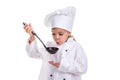 Girl chef white uniform isolated on white background. Holding black ladle and blowing to it. Looking at the ladle Royalty Free Stock Photo