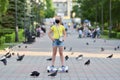Girl child in a black protective mask rides on a hoverboard past pigeons in a park during the COVID-19 pandemic