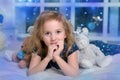 Child blonde in a blue dress lies on the bed with many toy bears Royalty Free Stock Photo