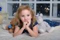 Child blonde in a blue dress lies on the bed with many toy bears Royalty Free Stock Photo