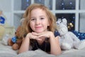 Child blonde in a blue dress lies on the bed with many toy bears Royalty Free Stock Photo