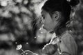 Girl child blowing on a dandelion flying seeds