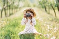 Girl child with a camera sitting in nature. Little girl taking photos with a vintage camera