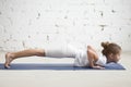 Girl child in chaturanga dandasana pose, white studio, closeup