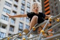 Girl child climbed to the top of the alpine grid on the playground