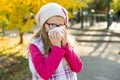 Girl child with cold rhinitis on autumn background, flu season, allergy runny nose Royalty Free Stock Photo