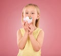Girl child, cupcake and portrait in studio on a pink background while eating cake. Face of a female kid model with a