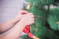 Girl, child decorates Christmas tree on white brick wall background