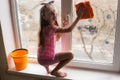 Girl child detergent with rag cleaning house, washing windows, springtime Royalty Free Stock Photo