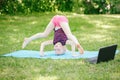 Girl child doing sport workout outdoor online. Video yoga stretching on Internet in park. Kid learning fitness gymnastics on Royalty Free Stock Photo