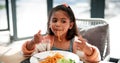 Girl, child and eating spaghetti in home, hungry and lunch with thinking at table in dining room. Kid, plate and