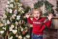 Girl child emotionally rejoices by opening mouth and raising hands at Christmas