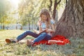 Girl child in glasses reading book in the park, on the grass near the tree Royalty Free Stock Photo