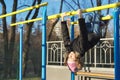 Girl child hanging upside down on outdoor sports playground with eyes closed Royalty Free Stock Photo