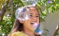Girl, child and happy with bubbles in garden for playing, excited or outdoor on vacation in summer. Kid, smile and soap Royalty Free Stock Photo