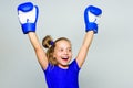 Girl child happy winner with boxing gloves posing on grey background. Feminist movement. She feels as winner. Upbringing