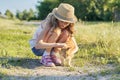 Girl child in hat on country road plays with red cat, sunny summer day rustic style Royalty Free Stock Photo