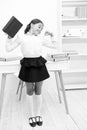 Girl child hold book while stretching white interior. Kid school uniform making exercise stretching increase Royalty Free Stock Photo