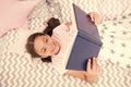 Girl child lay bed read book top view. Encourage useful habits.Kid prepare to go to bed. Pleasant time in cozy bedroom Royalty Free Stock Photo