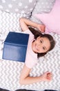 Girl child lay bed read book top view. Kid prepare to go to bed. Pleasant time in cozy bedroom. Girl kid long hair cute Royalty Free Stock Photo