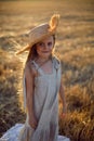 Girl child with long hair walking across the field wearing a hat