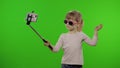 Girl child makes selfie, blogging on mobile phone using selfie stick. Chroma key Royalty Free Stock Photo