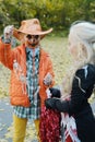 Girl child in an orange jacket and a cowboy hat shows her friend in a cheerleader costume her skeletons on a rope Royalty Free Stock Photo